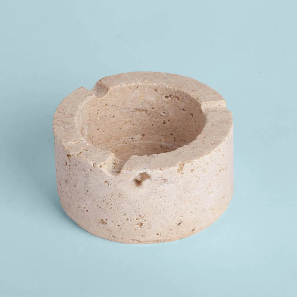 Beige ceramic ashtray on a light blue background