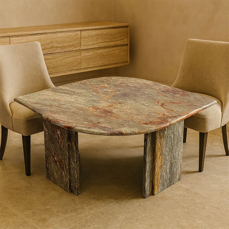 Dining table with marble-like surface and marble legs in a room with beige walls and chairs.